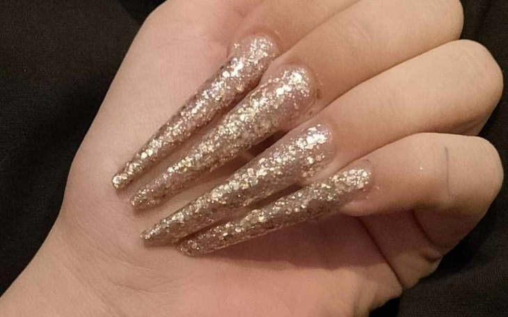 Dłonie z długimi, brokatowymi paznokciami.