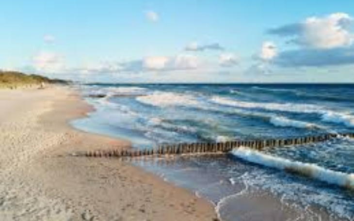 Plaża z falami i chmurami na niebie.