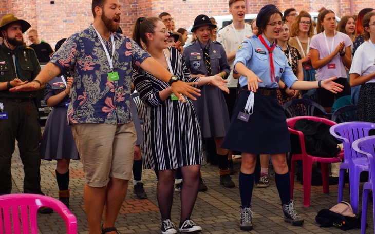 Grupa ludzi tańczących i śpiewających na wydarzeniu.