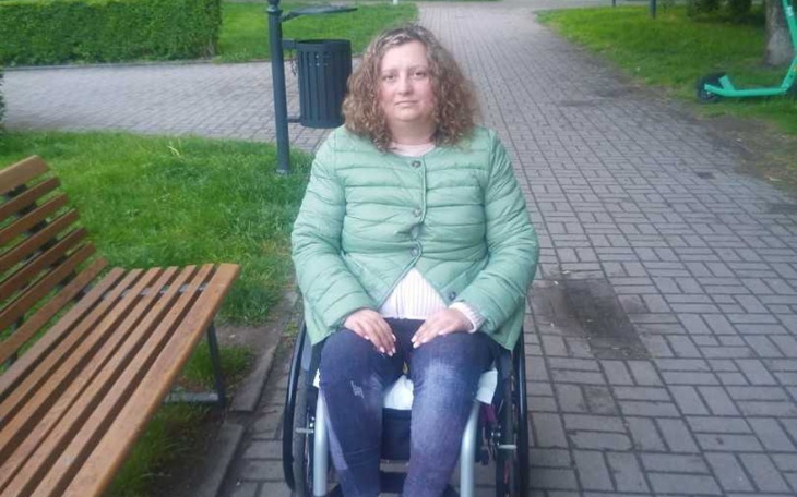 Kobieta w wózku inwalidzkim na spacerze w parku.
