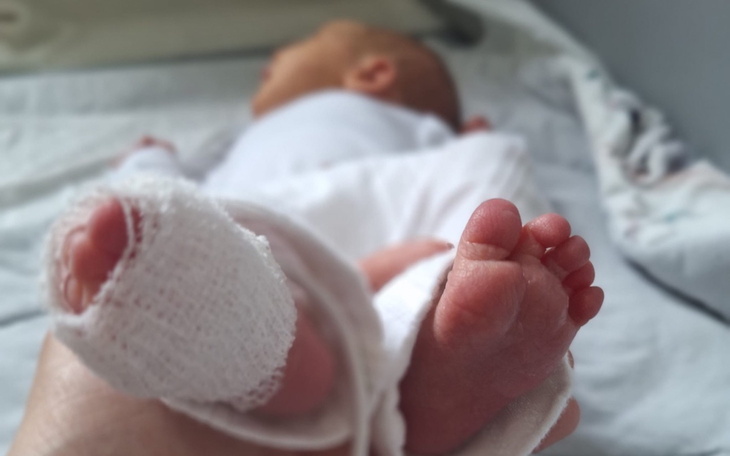 Małe stópki noworodka z bandażem na nodze.