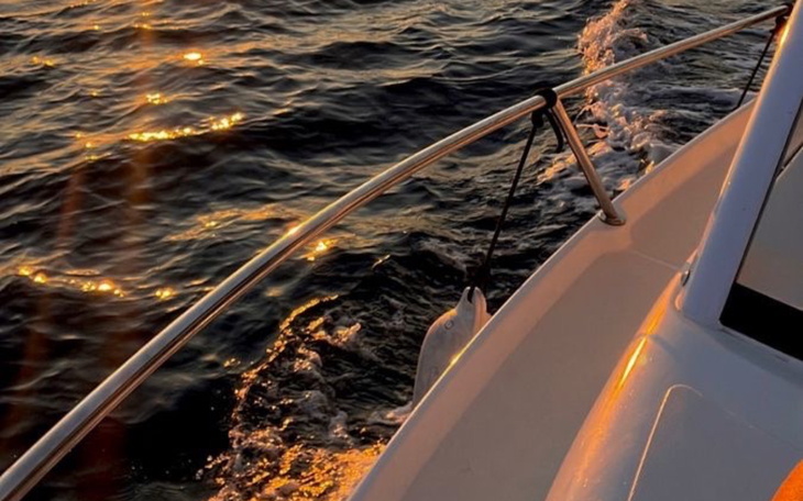 Widok na łódź na wodzie, odbijające się słońce.