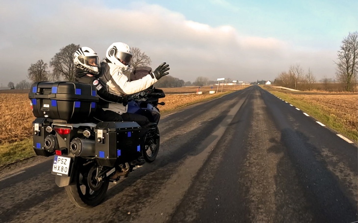 Motocykliści na drodze, cieszący się podróżą w pięknej scenerii.