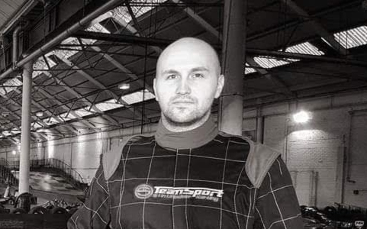 Mężczyzna w kombinezonie wyścigowym na torze.