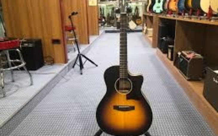 Gitara akustyczna na stojaku w sklepie muzycznym.