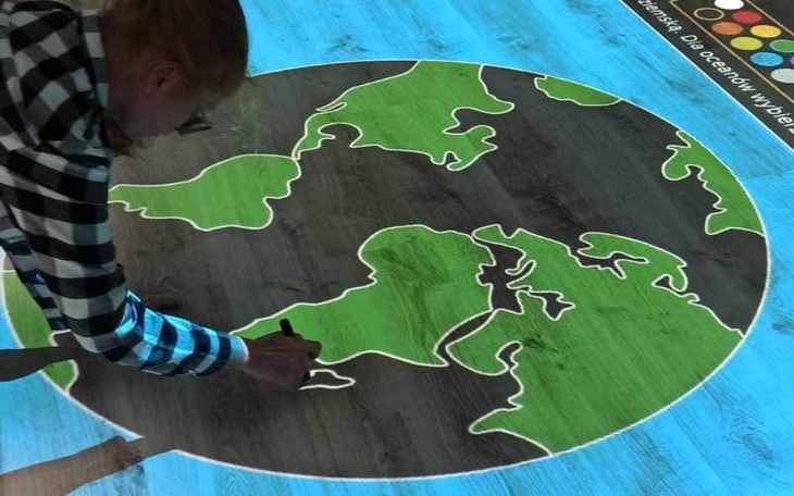 Osoba rysująca na interaktywnej podłodze z mapą.