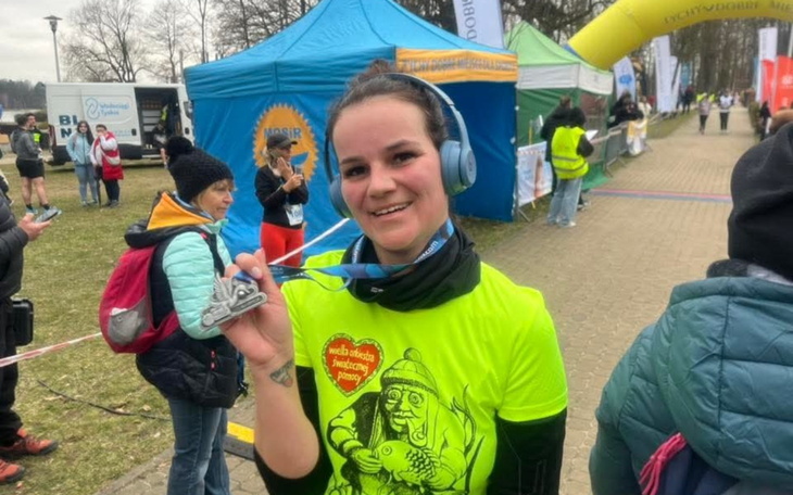 Biegaczka z medalem na szyi, uśmiechnięta po zawodach.