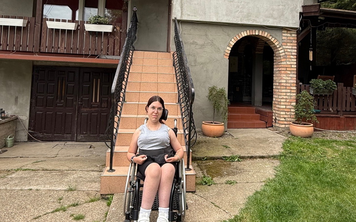 Dziewczyna na wózku inwalidzkim przed domem.