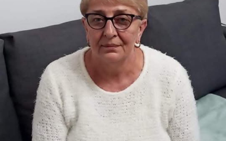 Kobieta w swetrze, siedząca na kanapie, z poważnym wyrazem twarzy.