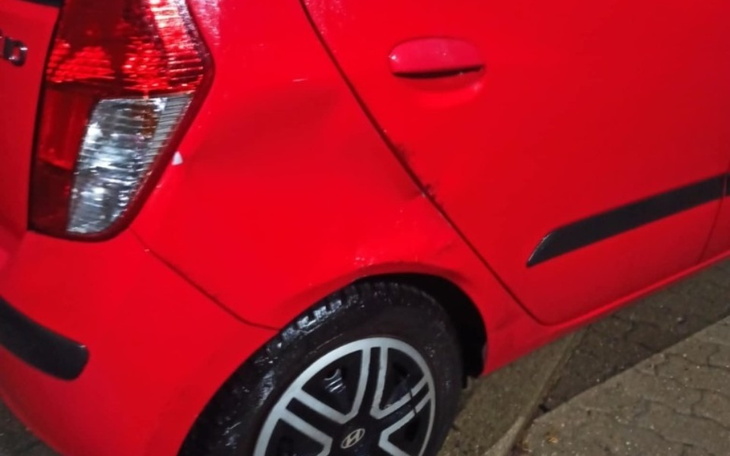 Czerwony samochód z widocznym uszkodzeniem na tylnym błotniku.