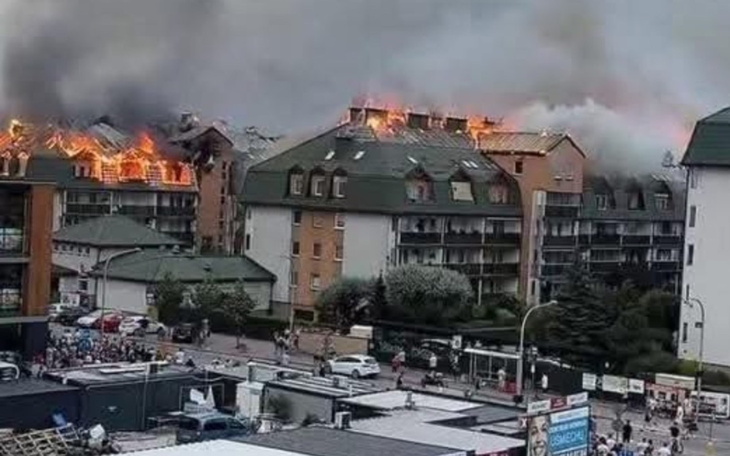 Pożar budynku mieszkalnego, dym i płomienie na dachu.