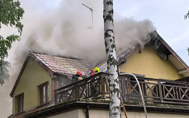 Strażacy gaszący pożar na dachu budynku.