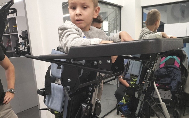 Chłopiec w specjalnym urządzeniu, wygląda na skupionego.