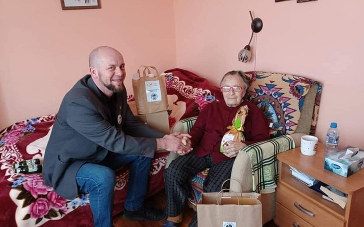 Mężczyzna podaje torbę starszej pani w przytulnym wnętrzu.