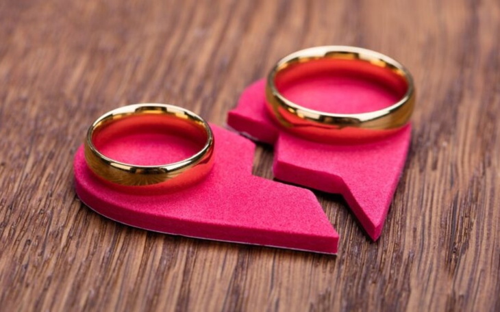 Złote obrączki na rozdzielonym sercu z papieru.