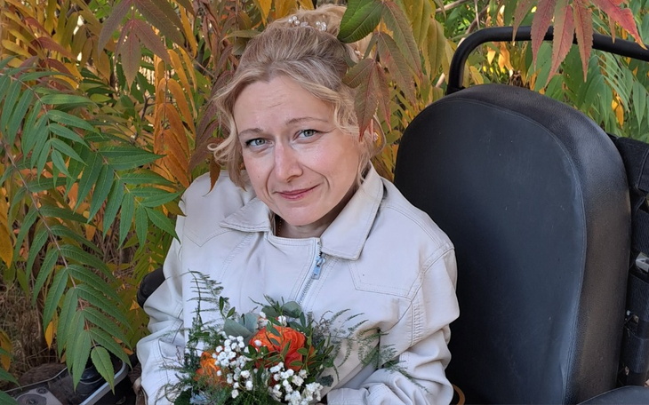 Kobieta z bukietem kwiatów wśród kolorowych liści.