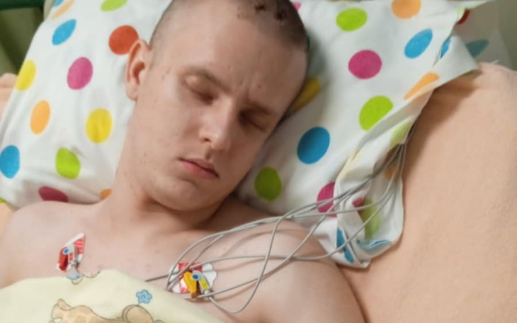 Młody mężczyzna w szpitalnym łóżku, z elektrodami na klatce piersiowej.