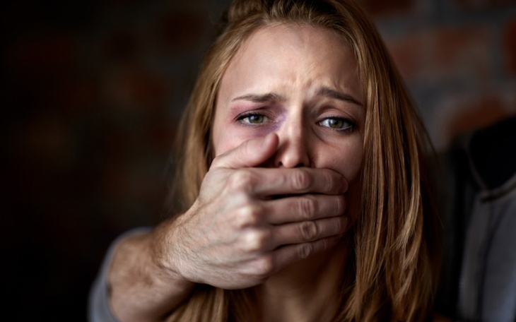 Kobieta z przerażonym wyrazem twarzy, zakryta ręką.