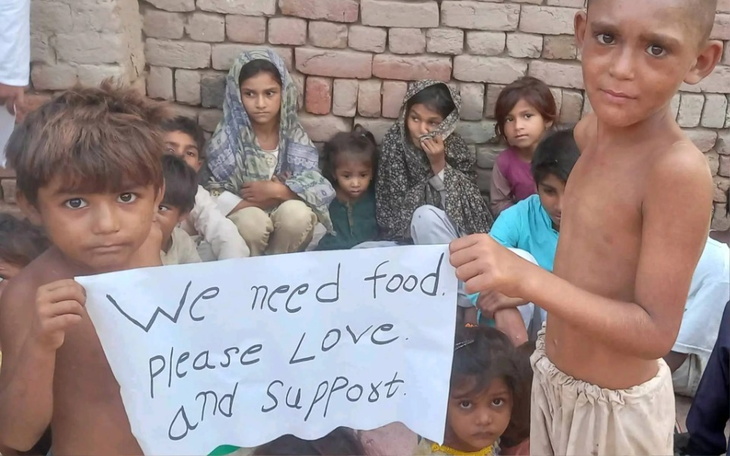 Dzieci trzymające transparent z prośbą o jedzenie i wsparcie.