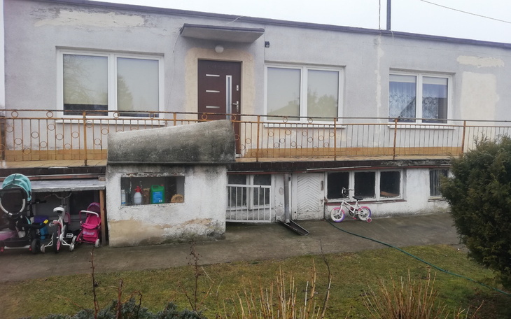 Widok na dom z tarasem i wózkami dziecięcymi na podjeździe.
