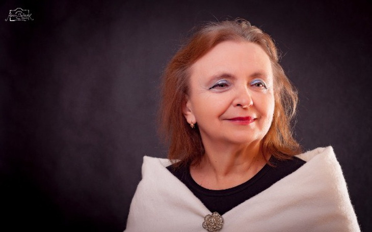 Portret kobiety w białym szalu na ciemnym tle.