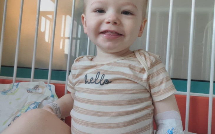 Małe dziecko w łóżeczku szpitalnym, uśmiechające się.