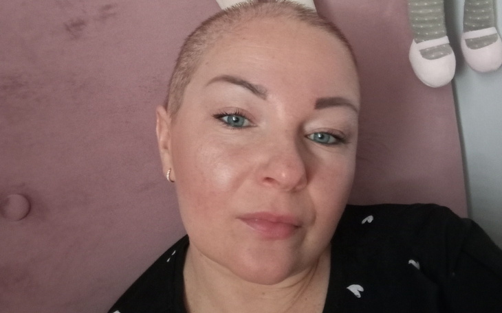 Portret kobiety z krótkimi włosami, uśmiechającej się do kamery.