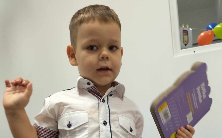 Chłopiec z książką, wygląda na zainteresowanego i radosnego.