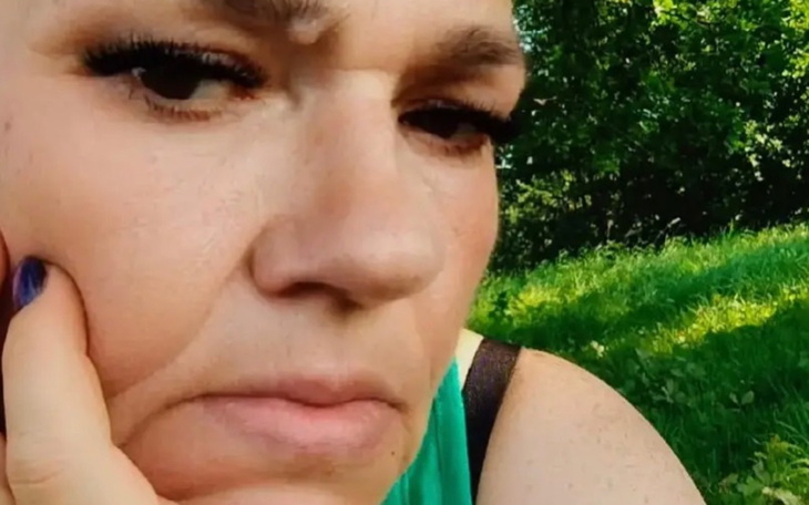 Kobieta z zamyśloną miną, siedząca na trawie.