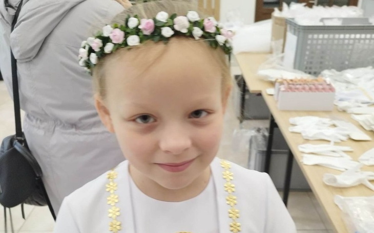 Mała dziewczynka w białej sukience z kwiatami we włosach.