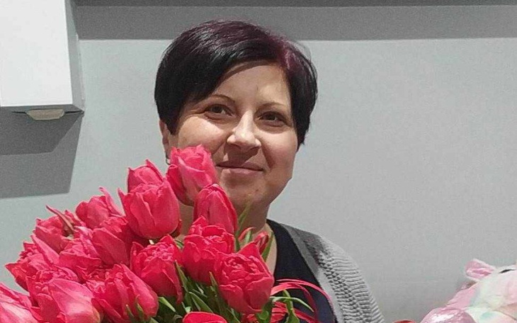 Kobieta trzymająca bukiet różowych tulipanów, uśmiechająca się.