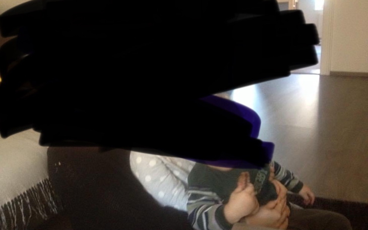 Dziecko na kolanach dorosłego, oboje w domowym otoczeniu.