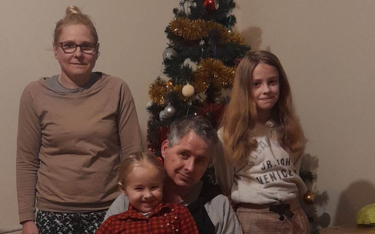 Rodzina pozująca przy choince, uśmiechnięta i szczęśliwa.