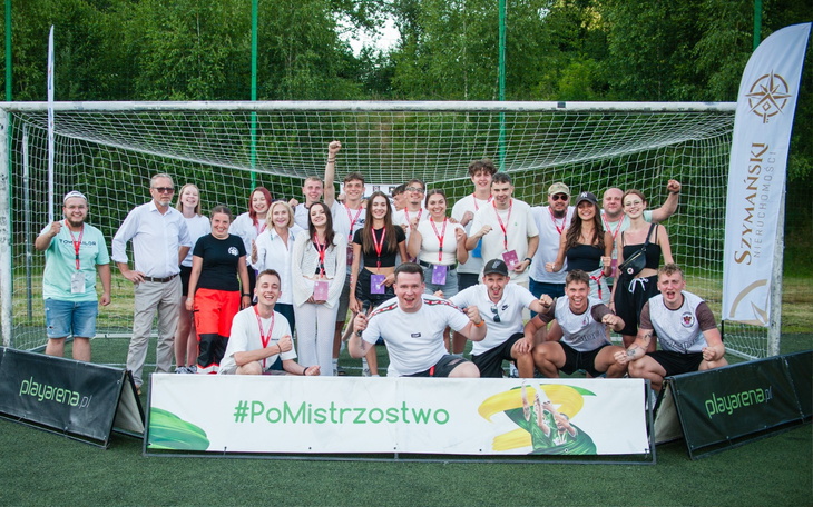 Grupa ludzi na boisku, świętujących zwycięstwo w turnieju.