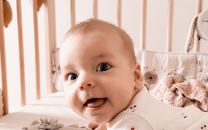 Uśmiechnięte niemowlę w łóżeczku, pełne radości.