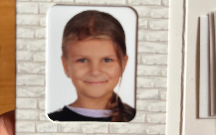 Portret uśmiechniętej dziewczynki na tle białej ściany.