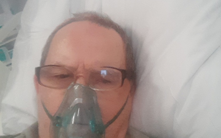 Mężczyzna w szpitalu z maską tlenową na twarzy.