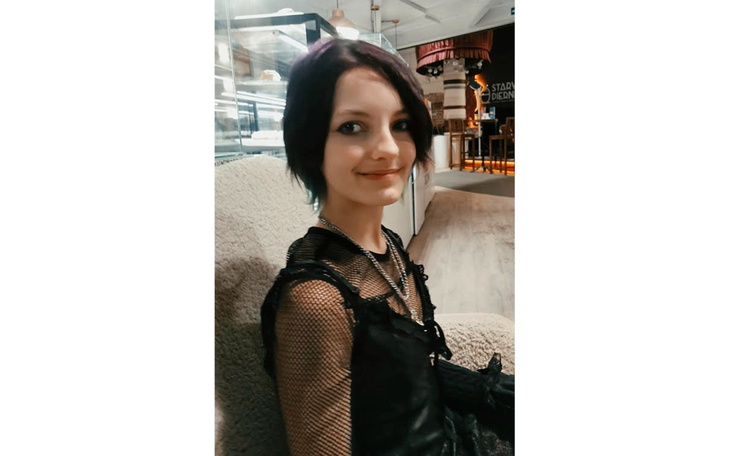 Młoda dziewczyna w modnym stroju, uśmiechnięta.