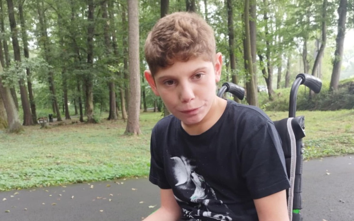 Chłopiec na wózku inwalidzkim w lesie.