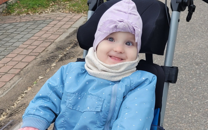 Mała dziewczynka w wózku, uśmiecha się radośnie.