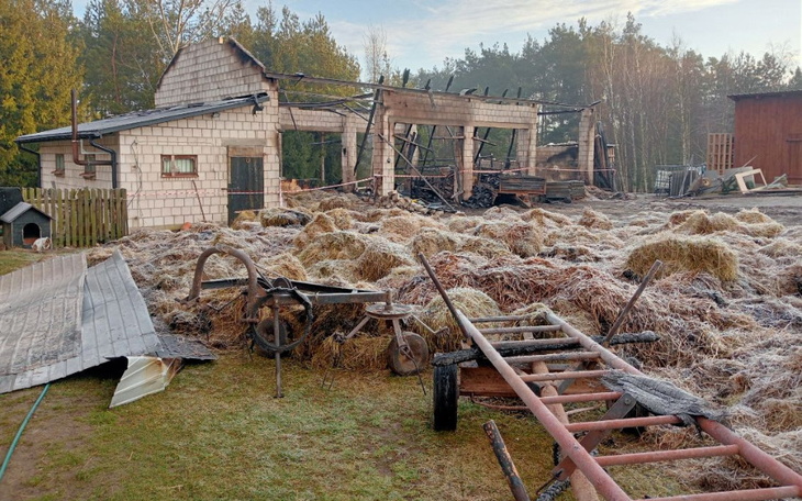 Zniszczony budynek po pożarze, otoczony stertami siana.
