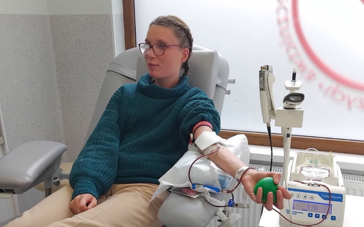 Osoba oddająca krew w klinice, z uśmiechem na twarzy.