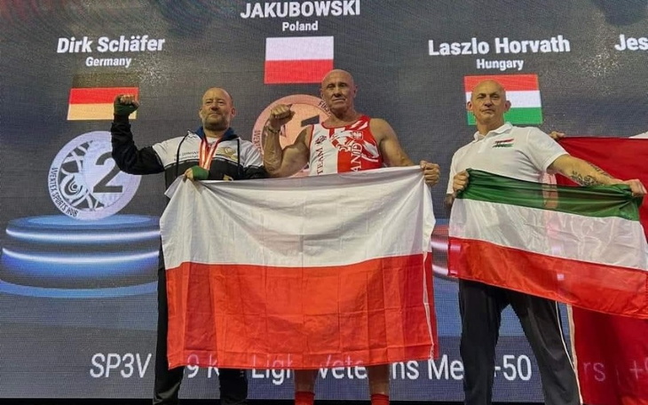 Trzech mężczyzn na podium, trzymających flagi swoich krajów.