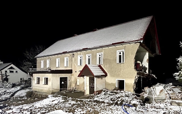 Zniszczony dom pokryty śniegiem, w nocy.