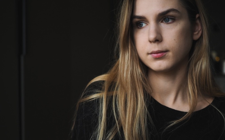 Portret młodej kobiety z długimi włosami, patrzącej w dal.