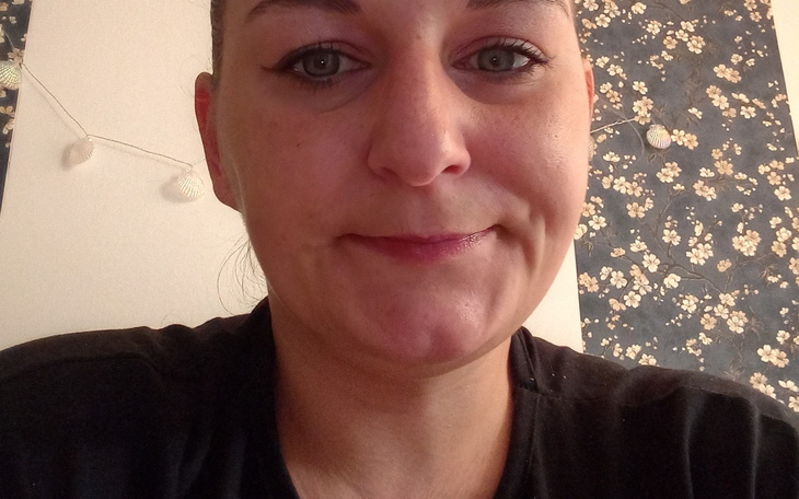 Portret uśmiechniętej kobiety w kwiecistej scenerii.