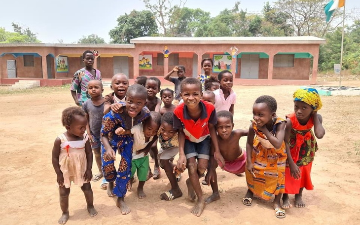 Grupa dzieci bawi się na podwórku, uśmiechnięte i radosne.