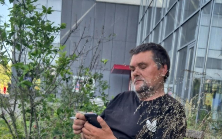 Mężczyzna siedzący na ławce, korzysta z telefonu.