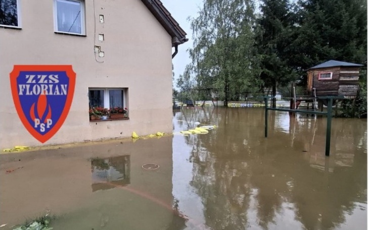 Zalane podwórko z widocznymi workami przeciwpowodziowymi.