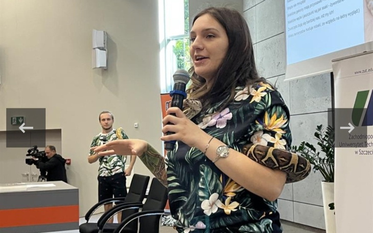 Prezentacja z wężem na ramieniu, uczestnicy w tle.